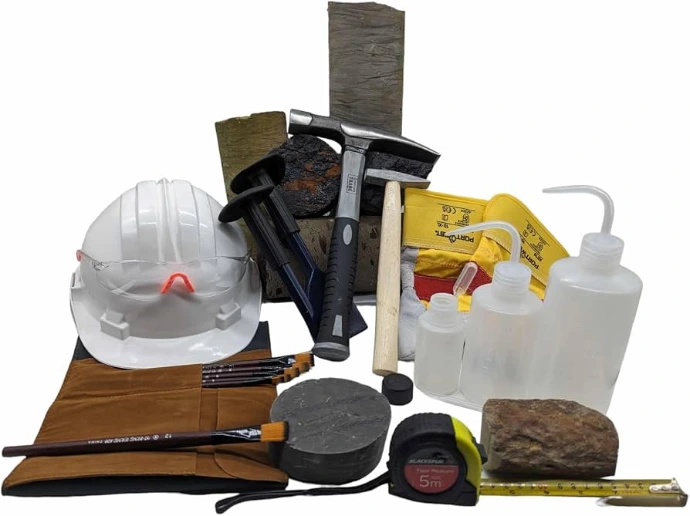Geological field kit: hard hat, rock hammers, hand lens, sample bags, wash bottles, tape measure and rock samples