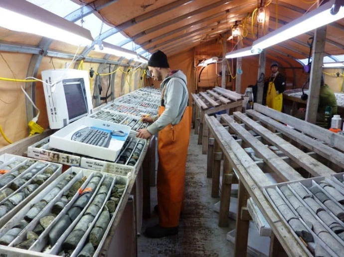 Geologist logging drill core in core boxes inside a core shack